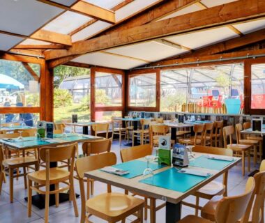 Salle de restaurant couverte avec tables et chaises au Camping de l’Etang du Pays Blanc