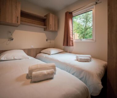Chambre avec deux lits et serviettes dans le mobil-home du Camping de l'Orangerie de Lanniron