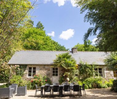 Patio et terrasse avec table et chaises devant maison en pierre du Camping de l'Orangerie de Lanniron