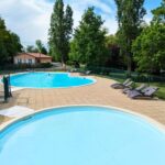 Piscines extérieures et pataugeoire entourées d'arbres au Camping de la Bageasse
