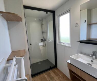 Salle d'eau avec douche vitrée lavabo et fenêtre dans le Camping de la Bageasse