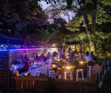 Terrasse extérieure animée le soir avec guirlandes lumineuses au Camping de la Bageasse