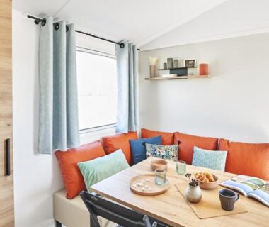 Coin repas avec banquette orange et table en bois au Camping de la Bonnette