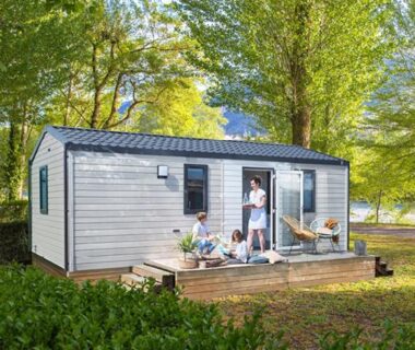 Terrasse avec mobil-home en bois entourée d'arbres au Camping de la Bonnette