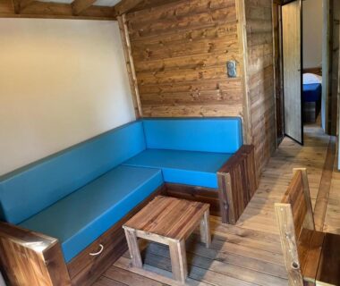 Coin salon avec banquette bleue et table basse dans mobil-home au Camping de la Dune Les Flots Bleus