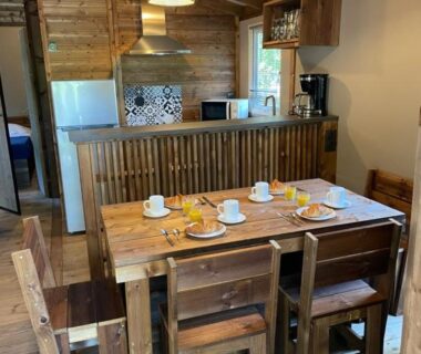 Intérieur avec coin cuisine et table en bois dans le chalet du Camping de la Dune Les Flots Bleus