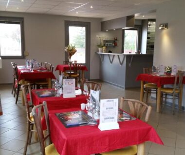 Salle à manger avec tables nappées de rouge au Camping de la Pelouse