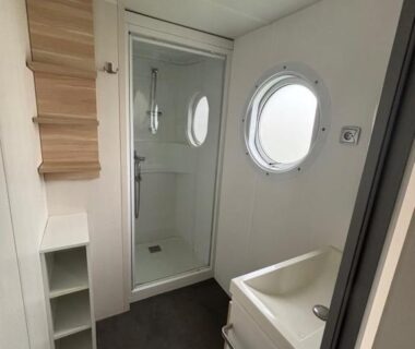 Salle de bain avec cabine de douche et hublot au Camping de la Plage