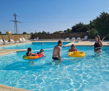 Piscine extérieure avec adultes et enfants en bouées au Camping de la Rive