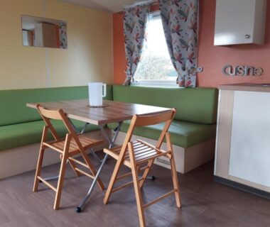 Coin repas dans l'hébergement avec banquette et kitchenette au Camping de la Rive