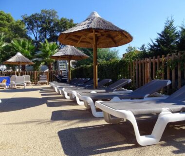 Bord de piscine avec transats et parasols au Camping de la Treille