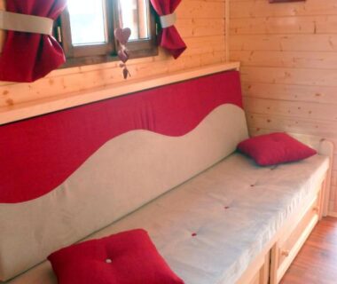 Intérieur en bois avec banquette et coussins au Camping de la Treille