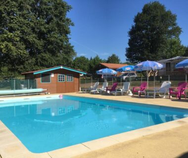 Piscine extérieure avec parasols et transats au Camping des Papillons