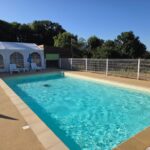 Piscine extérieure avec chaises et chapiteau au Camping des Papillons
