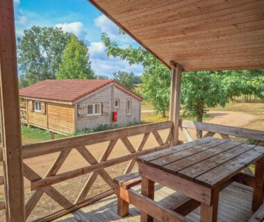 Terrasse en bois avec table et vue sur un chalet au Camping des Papillons