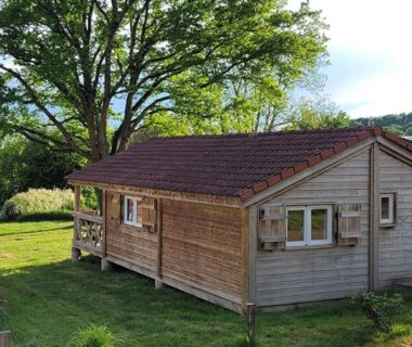 Chalet en bois sur pelouse avec arbres au Camping des Papillons