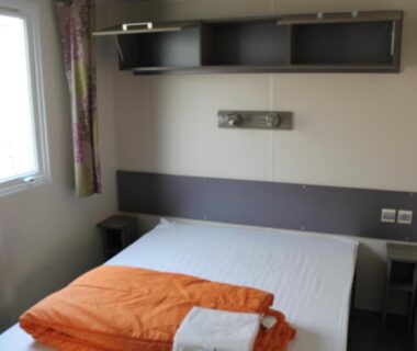 Chambre avec lit double et fenêtre au Camping des Roses