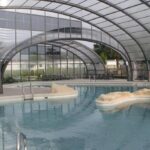 Piscine couverte sous verrière avec îlots et bassins au Camping des Roses