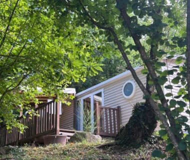 Mobil-home avec terrasse entouré d'arbres au Camping domaine Saint Martin 4 étoiles