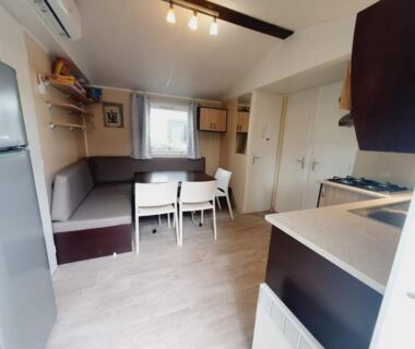 Intérieur salon avec kitchenette et coin repas du mobil-home confort 3 ch 2 clims au Camping domaine des Iscles