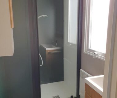 Salle de bain avec douche vitrée et lavabo dans l'hébergement du Camping du Bois Dormant
