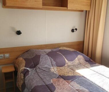Chambre double lumineuse avec rangements et lampes de lecture au Camping du Bois Dormant
