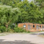 Allée bordée d'arbres et mobil-home en bois au Camping du Chêne