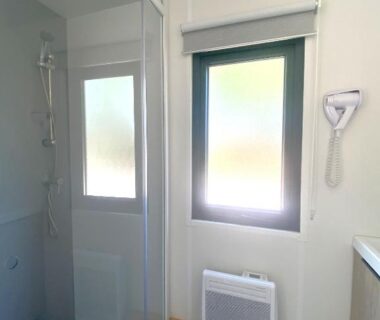 Salle d'eau avec cabine de douche fenêtre et sèche-cheveux au Camping du Chêne proche de Nantes
