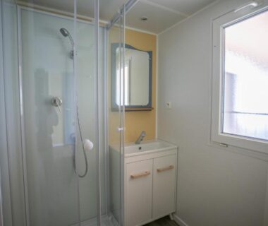 Salle d'eau avec cabine de douche lavabo et fenêtre du Camping du Lac