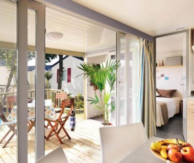 Terrasse en bois avec table et chaises ouvrant sur intérieur du mobil-home au Camping du Lac