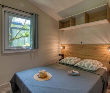 Chambre avec lit double et fenêtre au Camping du Lac de Grolejac