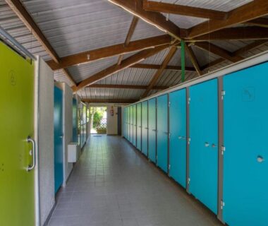 Couloir de vestiaires aux portes bleues et vertes au Camping du Lac de Grolejac