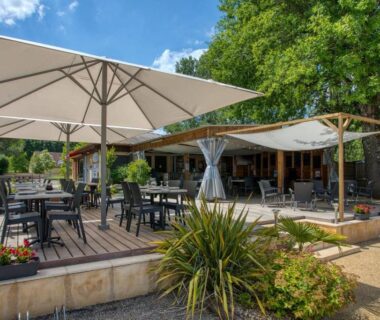Terrasse extérieure avec parasols et tables au Camping du Lac de Grolejac