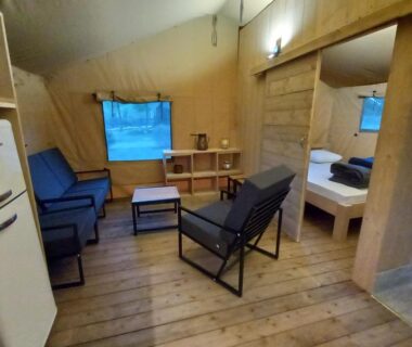 Intérieur de tente avec coin salon et lit au Camping du Moulin de Thoard