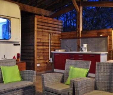 Terrasse couverte avec salon en rotin et kitchenette au Camping du Moulin de Thoard