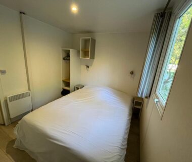 Chambre avec lit double et fenêtre dans le logement du Camping du Pont d'Avignon