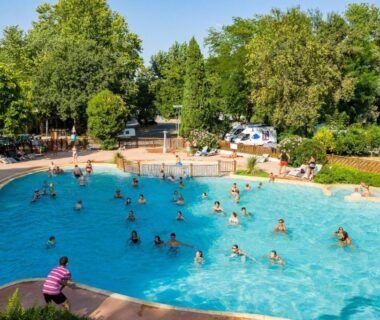 Piscine extérieure animée entourée d'arbres au Camping du Pont d'Avignon