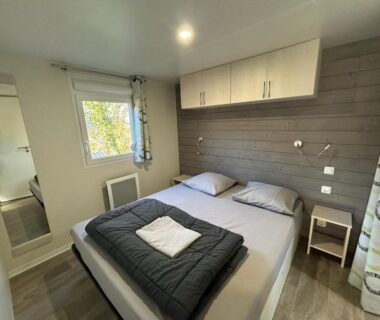 Chambre avec lit double et rangements au Camping du Valentin