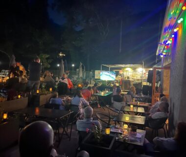 Terrasse extérieure avec tables et guirlandes lumineuses au Camping du Valentin