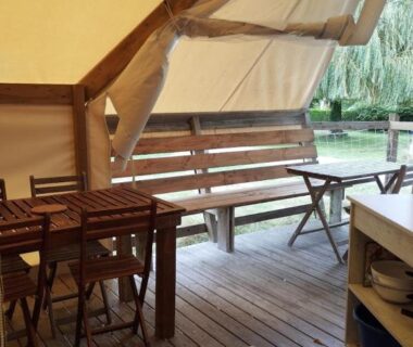 Terrasse en bois avec table et banc donnant sur l'eau au Camping du pont d'Oust