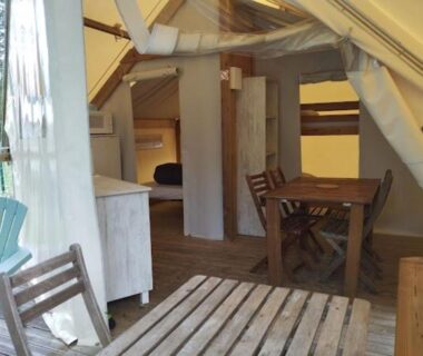 Intérieur de tente lodge avec table et chaises au Camping du pont d'Oust