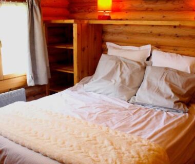 Chambre en bois avec lit et lumière chaude dans le camping écovillage Soleil du Pibeste