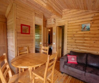 Salon et coin repas dans un chalet en bois au Camping écovillage Soleil du Pibeste