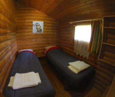 Cabine en bois avec deux lits et serviettes au camping écovillage Soleil du Pibeste