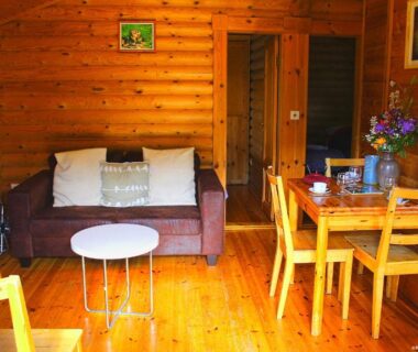 Intérieur de chalet avec canapé et coin repas au Camping écovillage Soleil du Pibeste
