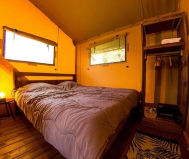 Intérieur de tente avec lit et lampe au Camping et Lodges de Coucouzac