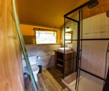 Salle de bains avec douche vitrée et toilettes dans le Camping et Lodges de Coucouzac