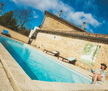 Piscine extérieure avec transats et personne assise au Camping et Lodges de Coucouzac