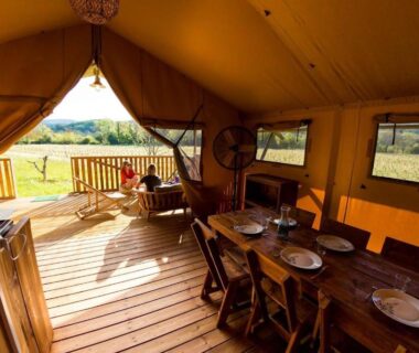 Intérieur de lodge avec coin repas et terrasse donnant sur la campagne au Camping et Lodges de Coucouzac
