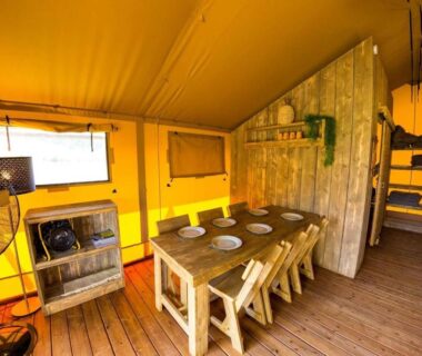 Intérieur de lodge avec table à manger et lits superposés au Camping et Lodges de Coucouzac